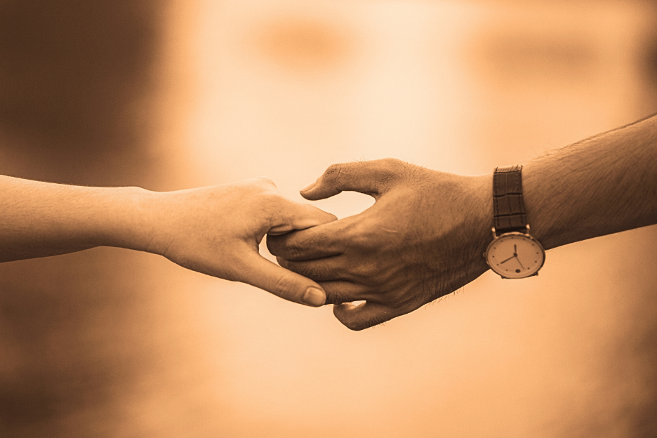 A man and a woman’s hand touching representing a deep connection and a meaningful relationship. Showing that it’s worth turning a crisis to connection and benefitting from a deep and meaningful relationship.